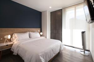 une chambre avec un lit blanc et une grande fenêtre dans l'établissement CLASS DE SUITES DE LUJO EL POBLADO. EXCELENTE UBICACIÓN, à Medellín