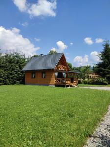 a log cabin in a field of grass with a house at Smrekowa Chatka w Milówce in Milówka