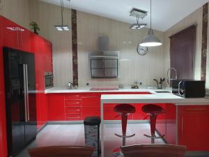 una cocina roja con armarios rojos y taburetes rojos en La Casa del Bosque, en El Bosque