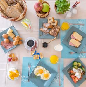 a table topped with plates of breakfast foods and orange juice at Agali bay hotel in Tinos