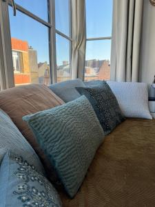 a couch with pillows sitting in front of a window at Maison Belle Rade : L’écoutille in Dunkerque