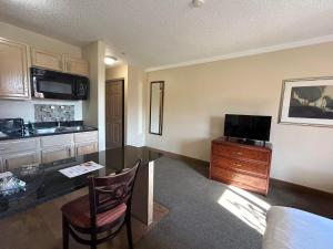 a room with a kitchen and a desk with a television at Ashley Quarters Hotel Airport-Cincinnati in Florence