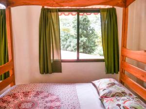 - une chambre avec un lit et une fenêtre avec des rideaux verts dans l'établissement Peace Retreat Costa Rica, à Playa Negra
