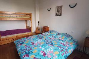 a bedroom with a bed with a colorful comforter and a guitar at Grand appartement proche Paris in Montreuil