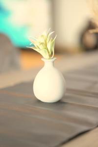 a white vase with a plant in it on a table at City Nook Apartments Near Hauptbahnhof in Vienna