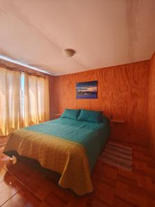 a bedroom with a bed in a wooden wall at Cabaña Queule in El Crucero