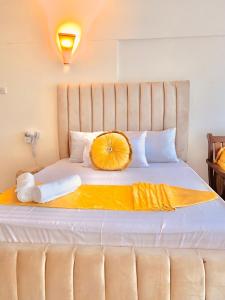 een groot bed met een oranje kussen erop bij Sophlin home in Ukunda