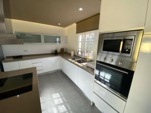 a kitchen with white cabinets and a stove top oven at SUNNY CARMELITO DELUXE in Mogán