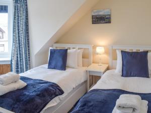 two beds in a room with blue and white at Corner Cottage in Girvan
