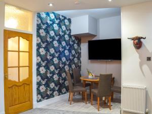 a dining room with a table and a tv at Largs Sunset in Largs