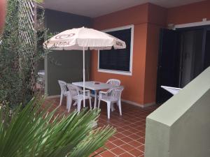 un patio con mesa, sillas y sombrilla en Appart Hotel Residence en Villasimius