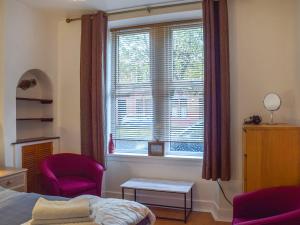 a bedroom with a bed and a window with two chairs at Largs Sunset in Largs