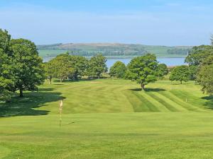 a view of a golf course with trees and a green at Largs Sunset in Largs