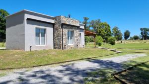 a house in a field with a driveway at Cabañas El Rincon in Tandil