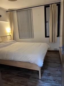 een slaapkamer met een groot bed met witte lakens bij 2 bedroom flat in Swansea