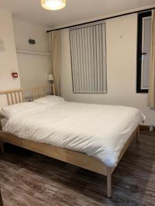 een slaapkamer met een bed met witte lakens en een raam bij 2 bedroom flat in Swansea