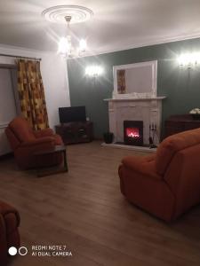 a living room with two chairs and a fireplace at Cosy 3 Bed Retreat in Omagh in Omagh