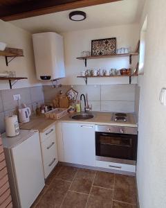 Elle comprend une petite cuisine avec des placards blancs et un évier. dans l'établissement Zlatni Hrast, à Pale