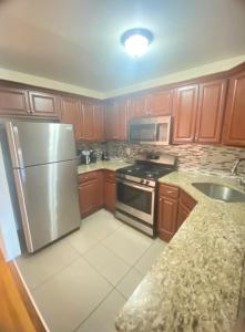 a kitchen with wooden cabinets and a stainless steel refrigerator at Fab 3 Bedroom 1Bath Apartment in NYC! in New York