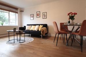 a living room with a black couch and a table at Perfect 2 Bedroom Flat Heathrow, Free Parking in Shepperton