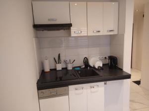 a kitchen with white cabinets and a sink at Trzy Korony Apartament in Nowy Sącz