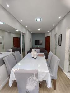 une salle à manger avec une table et des chaises blanches dans l'établissement Apartamento inteiro com área e garagem privativa, à Belo Horizonte