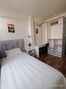 a bedroom with a large white bed and a desk at Casa Qura Qura in Cochabamba