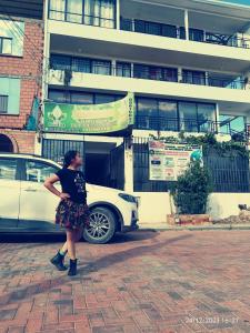 a woman standing next to a white car in front of a building at Casa Qura Qura in Cochabamba