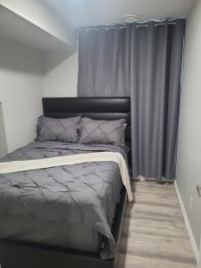 a bed in a room with gray curtains at Covenant Properties in Edmonton