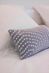 almohada gris sentada en una cama blanca en Hostal el Ranxo en Cadaqués