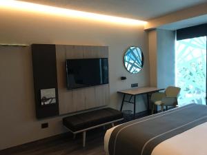 a hotel room with a bed and a flat screen tv at City Express Plus by Marriott Merida in Mérida
