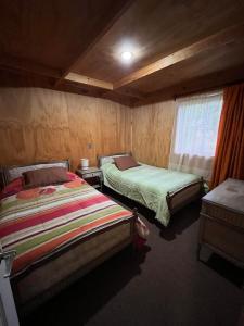 1 dormitorio con 2 camas y ventana en Cabañas Quilquico, en Quilquico