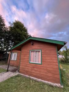 Cabañas Quilquico في Quilquico: منزل احمر صغير بسقف اخضر و نافذتين
