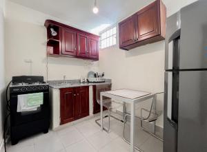 cocina con armarios de madera y nevera negra en Nice Central Studio Apartment, en Santo Domingo
