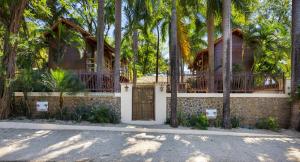 a house with a gate and palm trees at The Beach Bungalows - Yoga and Surf House - Adults Only in Tamarindo