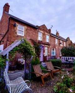 a house with two benches in front of it at Lilac Cottage Morpeth Northumberland in Morpeth