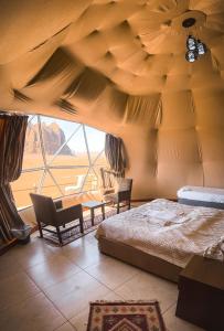 a bedroom with a bed and a large window at RUM ROYAL FLOWER lUXURY CAMP in Wadi Rum