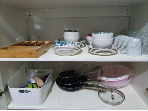 un estante con platos, tazas y tazones. en A little bedroom for you (3), en Warwick Farm