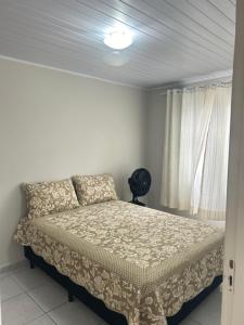 1 dormitorio con cama y ventana en Casa completa - Governador Celso Ramos à 15m da praia de palmas, en Governador Celso Ramos