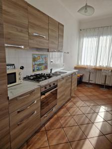 cocina con armarios de madera, fogones y microondas en Alloggio Turistico 3 minuti da aeroporto- Fiumicino centro, en Fiumicino