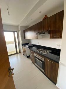 a kitchen with wooden cabinets and a stove top oven at appartements Mohammedia/mansouria in Pont Blondin