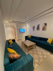 uma sala de estar com um sofá azul e uma mesa em appartements Mohammedia/mansouria em Pont Blondin
