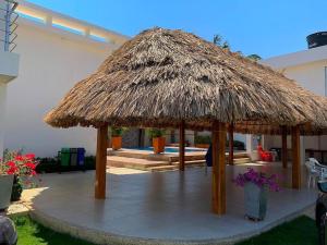 een grote rieten parasol op een patio met een zwembad bij Casa Campo Villa Rosa in Valledupar