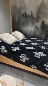 a bed with a black and white blanket and pillows at Górska Ostoja Gubałówka in Zakopane