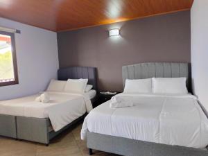 a bedroom with two beds and a window at Hotel PiedradeLuna in Villa de Leyva