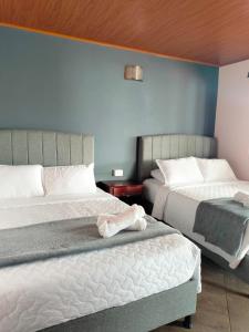 1 dormitorio con 2 camas y pared azul en Hotel PiedradeLuna en Villa de Leyva