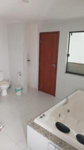 La salle de bains est pourvue d'une baignoire, de toilettes et d'un miroir. dans l'établissement R&L Pousada, à Cabo Frio