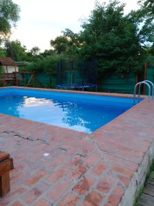 uma piscina azul com um parque infantil ao fundo em Santa Elena Hostal em Luján