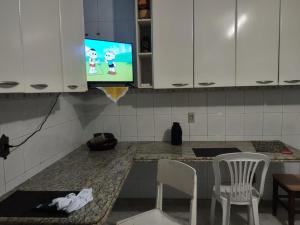 a kitchen with a tv and a table and chairs at Pousada Arvoredo in Contagem