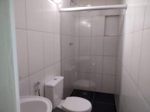 a white bathroom with a toilet and a sink at Pousada Arvoredo in Contagem